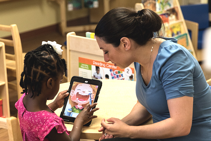 A teacher watching her student learn on an iPad