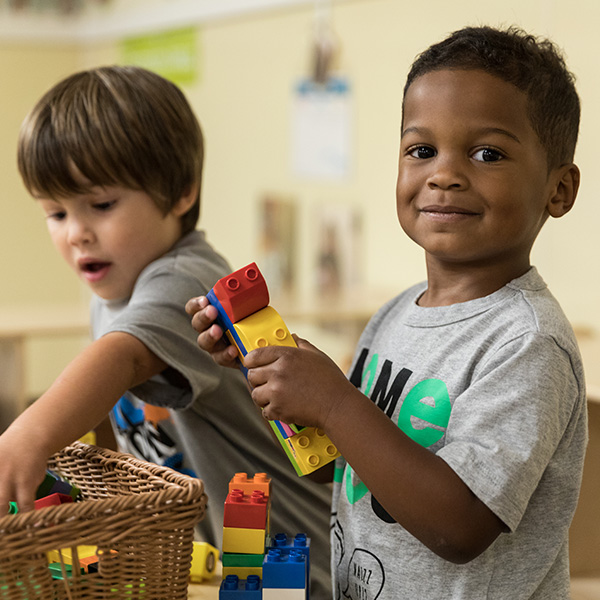 Two young boys playing with legos out of a basket