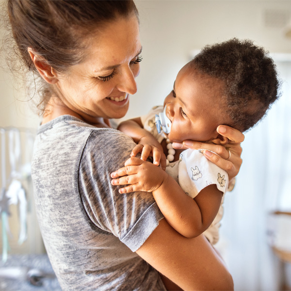 A mom holding her baby smiling