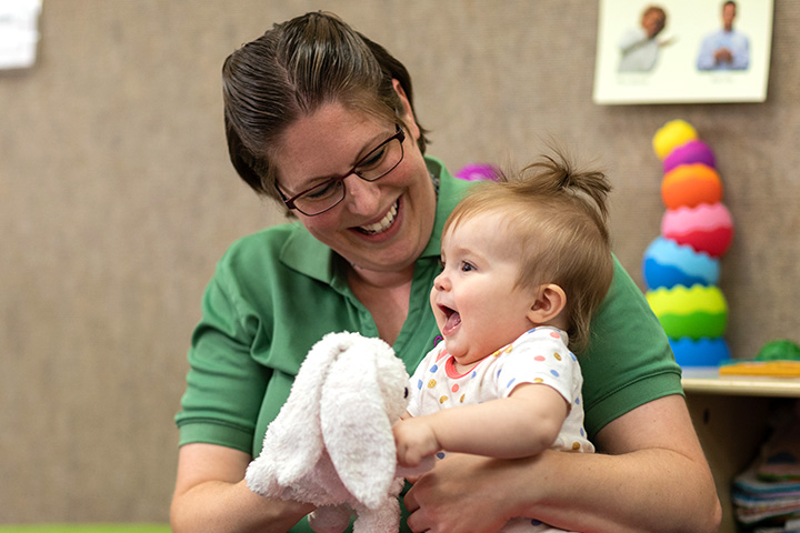 A teacher with a little girl smiling on her lap