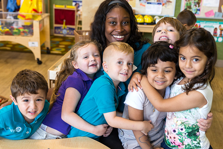 Teacher surrounded by kids hugging